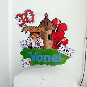 May include: A cake topper with a frog wearing a straw hat, holding a bottle and a can of Coors Light. The topper includes a Puerto Rico map, the name "YONEL", the number "30", and red hibiscus flowers.