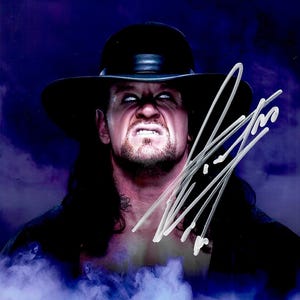 May include: A portrait of a man with a stern expression, wearing a black hat and dark clothing. His face is illuminated, with white eyes and a signature in the upper right corner. The background is a gradient of purple and blue.