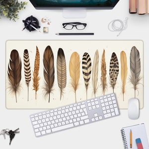 May include: A beige desk mat featuring a pattern of 12 brown, black and white feathers. The feathers are arranged in a row across the mat.