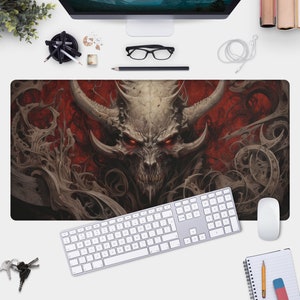 May include: A dark gray and red mousepad with a detailed illustration of a demonic creature with horns and glowing red eyes. The creature is surrounded by intricate, swirling patterns.