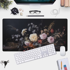 May include: A black desk mat with a floral design featuring a bouquet of pink, white, and yellow roses, lilies, and other flowers on a dark background.