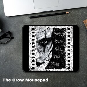 May include: Black and white mousepad with a graphic of a man's face with a black stripe down his face and the text "Can't Rain All The Time". The graphic is set against a film strip background.