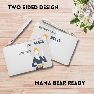 May include: Two-sided clutch purse with a white background and black text. One side features a woman in a black dress holding a gold clutch and the text "I have a Glock in my clutch". The other side features the text "And I know how to use it".