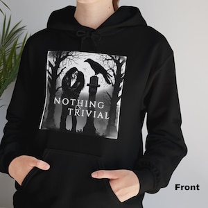 May include: Black hoodie featuring a graphic print of a couple standing in a graveyard with a raven perched on a tombstone. The text "NOTHING IS TRIVIAL" is printed below the image.