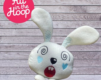 May include: White plush bunny with embroidered blue eyes, a red mouth, and black nose. The bunny has a swirling design on its eyes and blue hearts on its cheeks.