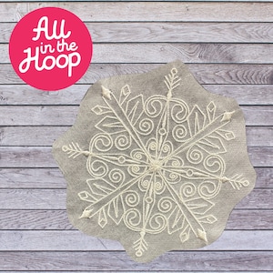 May include: A white snowflake embroidery design on a gray fabric background. The design features intricate swirls and lines, creating a delicate and elegant pattern.