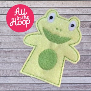 May include: Green felt finger puppet shaped like a frog with a big smile and white eyes.
