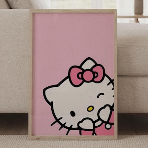 Può includere: Una stampa artistica da parete rettangolare incorniciata che presenta un'illustrazione grafica del personaggio Hello Kitty su uno sfondo rosa a tinta unita. Il personaggio è mostrato dal busto in su, indossa un fiocco rosa, con contorni neri.