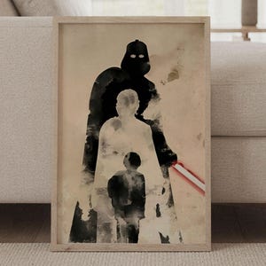 Op de afbeelding: Een rechthoekige ingelijste kunstdruk met een aquarel-stijl silhouet van een lange, donkere figuur met een gloeiend rood lichtzwaard, gelaagd over een lichter silhouet van een persoon en een klein kind, alles tegen een beige achtergrond.
