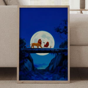 Puede incluir: Una lámina de arte mural rectangular en un marco de madera clara que muestra una escena nocturna azul oscuro con una gran luna llena. Un león, un jabalí y una suricata caminan sobre un tronco caído frente al cielo iluminado.