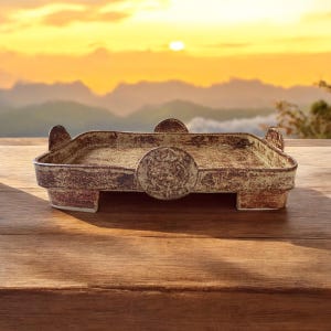 May include: A rectangular ceramic tray with a raised rim and a circular accent on the front. The tray is a mottled brown and tan color, with a rustic, textured appearance. The tray is on a wooden surface.