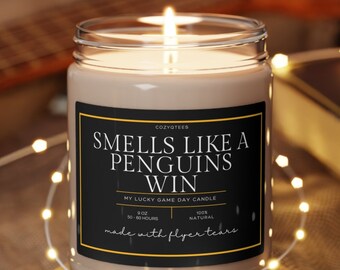 May include: A brown glass candle with a black label that reads "Smells like a penguins win" and "My lucky game day candle". The label also says "Made with flyer tears".