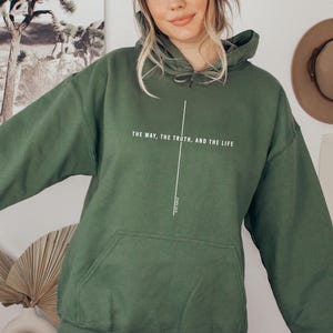 May include: A dark green hooded sweatshirt with the text "The way, the truth, and the life" printed on the front. The text is in white and is centered on the sweatshirt.