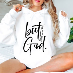 May include: White hoodie featuring the words "but God" in black script. The phrase "There was no way, but GOD made a way" is printed vertically to the right of "but". The hoodie has a drawstring hood and long sleeves.