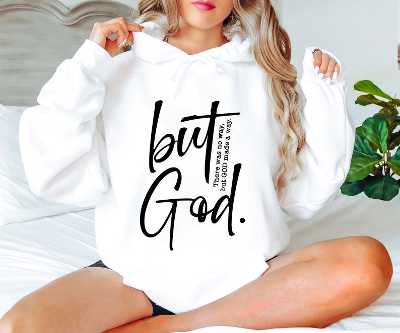 May include: White hoodie featuring the words "but God" in black script. The phrase "There was no way, but GOD made a way" is printed vertically to the right of "but". The hoodie has a drawstring hood and long sleeves.