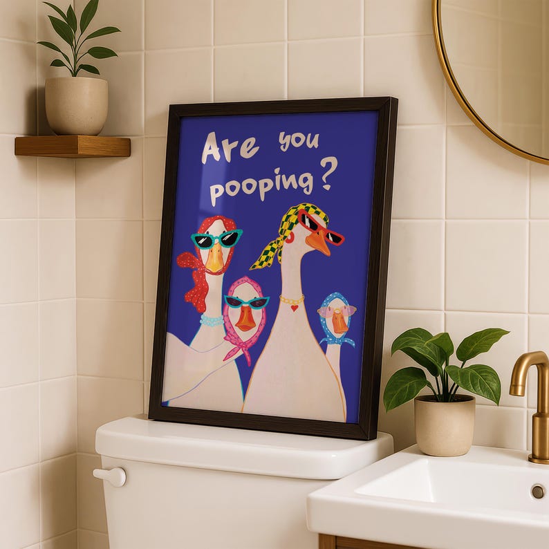 May include: Framed art print featuring a blue background with the text "Are you pooping?" and illustrations of three geese wearing sunglasses and scarves. The artwork is displayed above a toilet in a bathroom setting.