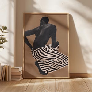 Könnte beinhalten: Ein gerahmter Kunstdruck mit einer schwarz-weißen Illustration einer Person in der Hocke. Die Person trägt eine gestreifte Hose. Der Hintergrund ist einfarbig beige.