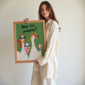 May include: A framed art print featuring a green background with the text "Are you pooping?". The artwork depicts three geese wearing sunglasses and scarves. The frame is made of light brown wood.