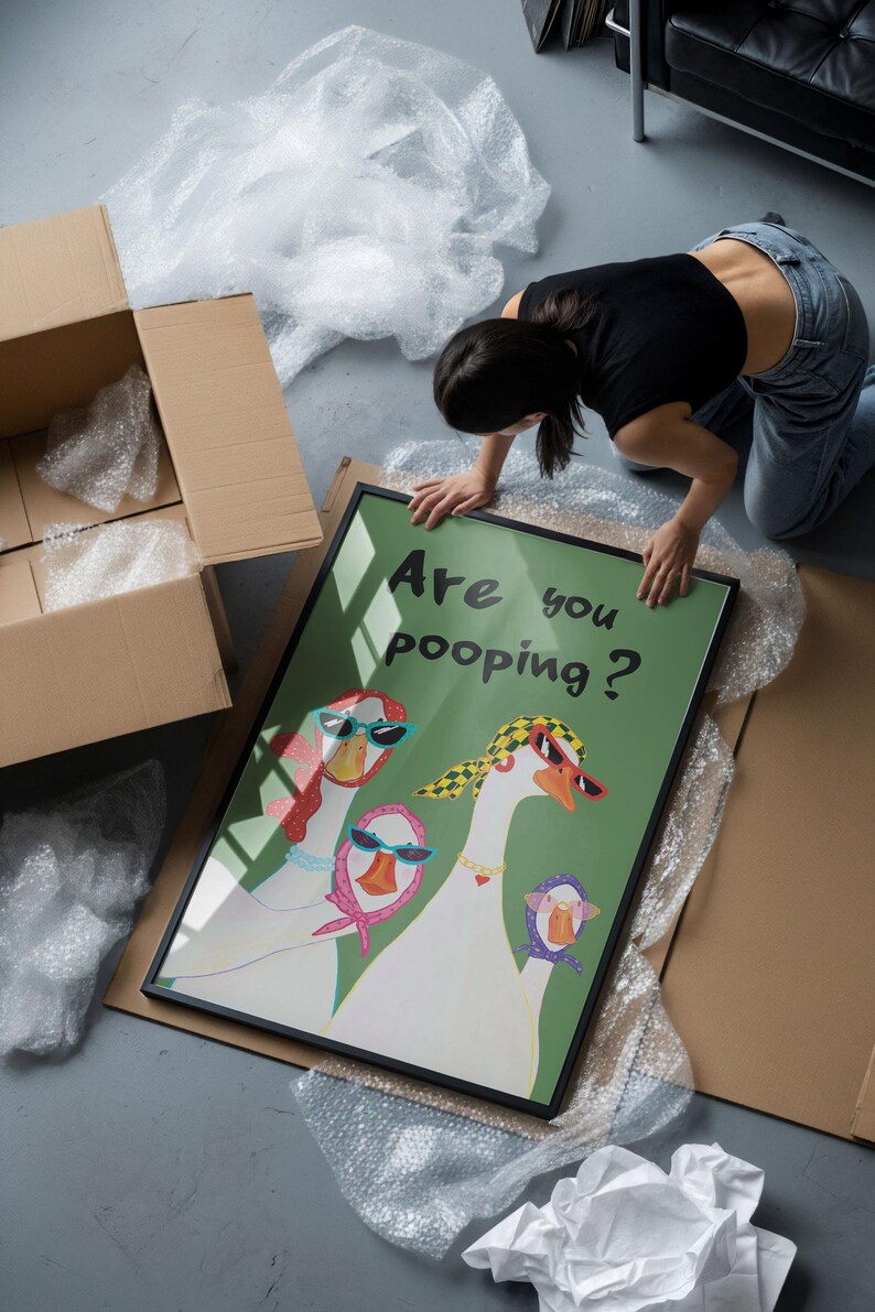 May include: A framed art print featuring three cartoon geese wearing sunglasses and scarves, with the text "Are you pooping?" on a green background. The artwork is in a black frame, surrounded by bubble wrap and cardboard.