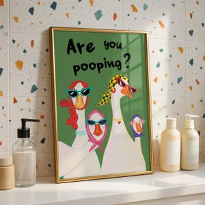 Illustrated geese standing in a row on a light green background, wearing headscarves and sunglasses, with the handwritten phrase “Are you pooping?” above them in playful lettering.