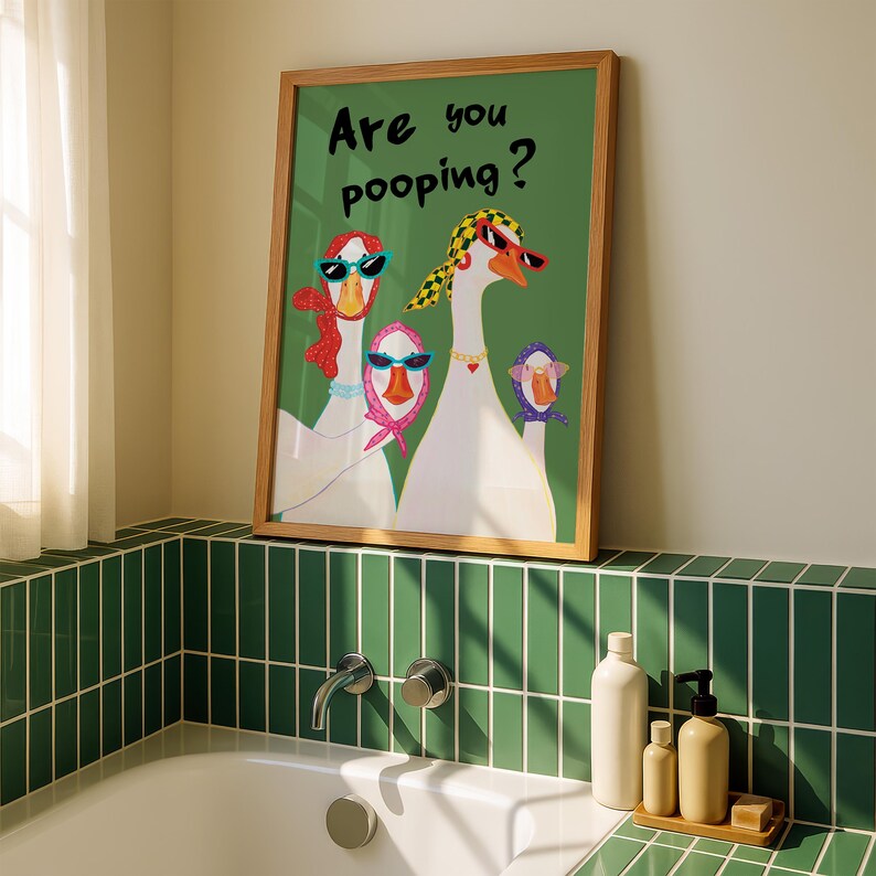 May include: A framed art print featuring a green background with the text "Are you pooping?" and illustrations of geese wearing sunglasses and scarves. The frame is made of wood.