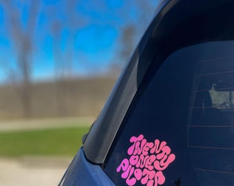 Può includere: Un adesivo "Twenty One Pilots" rosa e bianco sul lunotto posteriore di un'auto.