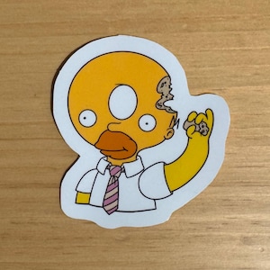 Può includere: Un personaggio dei cartoni animati giallo con una testa a forma di ciambella, che indossa una camicia bianca e una cravatta a righe rosa e bianche. Il personaggio tiene una ciambella nella sua mano destra.