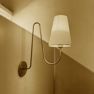 Aplique de pared enchufable, brazo curvo de latón con pantalla de lino.