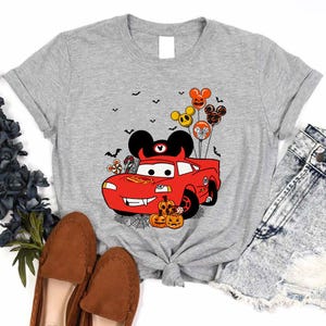 a gray shirt with mickey mouse driving a red car