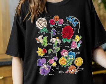 May include: Black t-shirt with a colorful illustration of various flowers, each labeled with a number and name, such as "Fig I. White Rose", "Fig II. Chrysanthemum", and "Fig III. Bluebells".