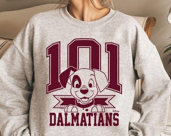 Może przedstawiać: Szara bluza z nadrukiem w kolorze bordowym przedstawiającym szczeniaka dalmatyńczyka z napisem "101 Dalmatyńczyków" i "Disney" poniżej.