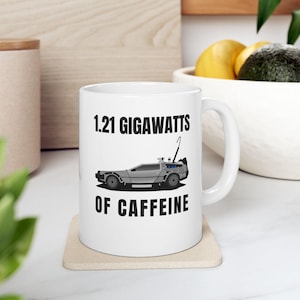 May include: White ceramic coffee mug with a black and white illustration of a DeLorean time machine and the text "1.21 Gigawatts of Caffeine".
