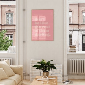 Puede incluir: Un p&oacute;ster enmarcado en rosa con el texto "don't be like the rest of them darling." El p&oacute;ster est&aacute; colgado en una pared blanca en un sal&oacute;n.