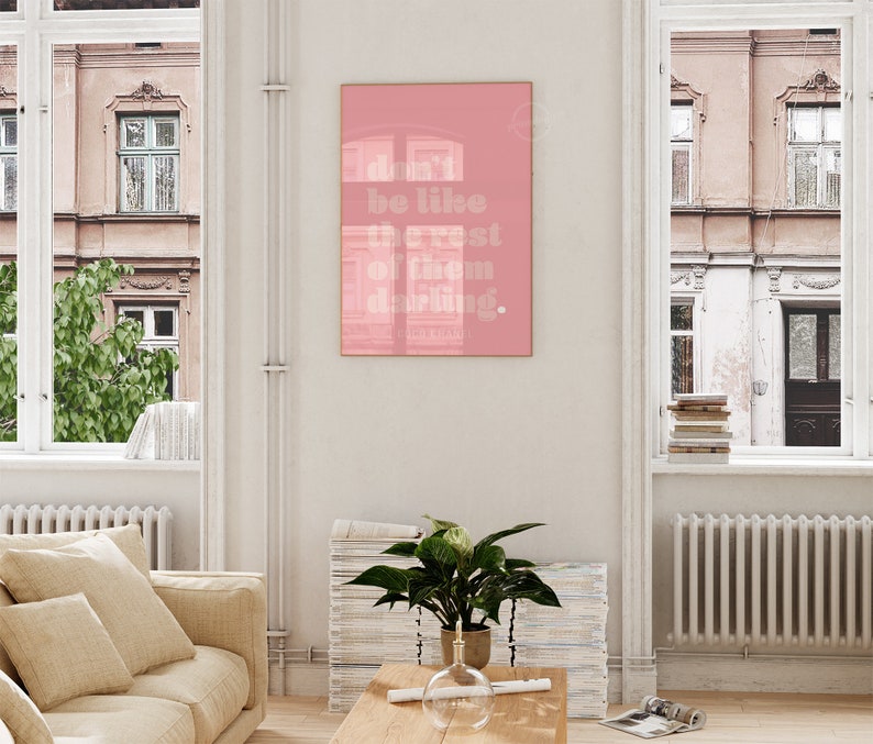 Puede incluir: Un p&oacute;ster enmarcado en rosa con el texto "don't be like the rest of them darling." El p&oacute;ster est&aacute; colgado en una pared blanca en un sal&oacute;n.