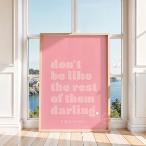 Puede incluir: P&oacute;ster rosa con una cita blanca que dice "no seas como los dem&aacute;s, querida". La cita se atribuye a Coco Chanel.