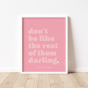 Puede incluir: Impresi&oacute;n enmarcada rosa con fondo blanco y el texto "don't be like the rest of them darling." El texto est&aacute; en negrita, en blanco. La parte inferior de la impresi&oacute;n tiene el texto "COCO CHANEL" en blanco, en una fuente m&aacute;s peque&ntilde;a.