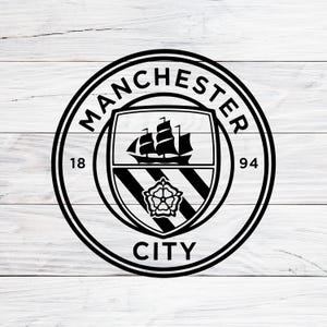 May include: A black circular emblem featuring the Manchester City football club logo. The design includes a central shield with a sailing ship above a rose, flanked by the numbers 18 and 94, all enclosed within a circular border with text.