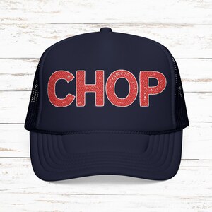 May include: Navy blue trucker hat with the word "CHOP" in distressed red lettering across the front. The hat has a mesh back and a curved brim. The hat is sitting on a white wooden surface.