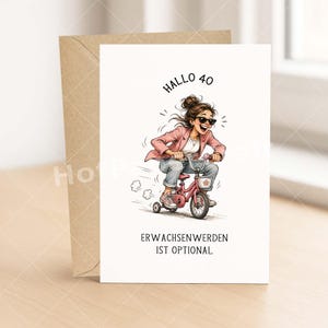 May include: Greeting card with a cartoon illustration of a woman riding a pink tricycle. The card has the text "Hallo 40" and "Erwachsenwerden ist optional". The card is paired with a brown envelope.