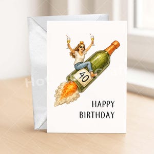 May include: A birthday card featuring a woman riding a champagne bottle rocket, holding two glasses of champagne. The bottle has a "40" label. The card reads "HAPPY BIRTHDAY" in black text. An envelope is visible in the background.