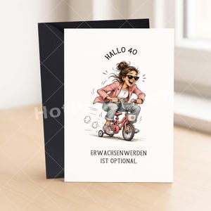 May include: Greeting card with a cartoon illustration of a woman riding a pink tricycle. The woman is wearing sunglasses, a pink blazer, and jeans. The text "Hallo 40" and "Erwachsenwerden ist optional" are printed on the card.