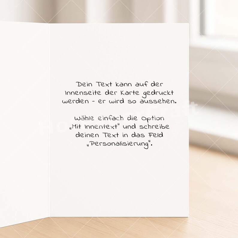 May include: A white greeting card with black handwritten text. The text is in German and describes how to personalize the inside of the card. The card is open, revealing the inside text.