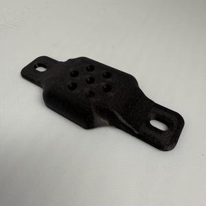 May include: A black, 3D-printed object with a rectangular shape and rounded edges. It features two holes on the ends and several smaller holes in the center. The object is likely a component or part of a larger assembly.