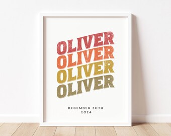 May include: A white framed print with the name "Oliver" repeated four times in a rainbow gradient, with the text "December 30th 2024" below.