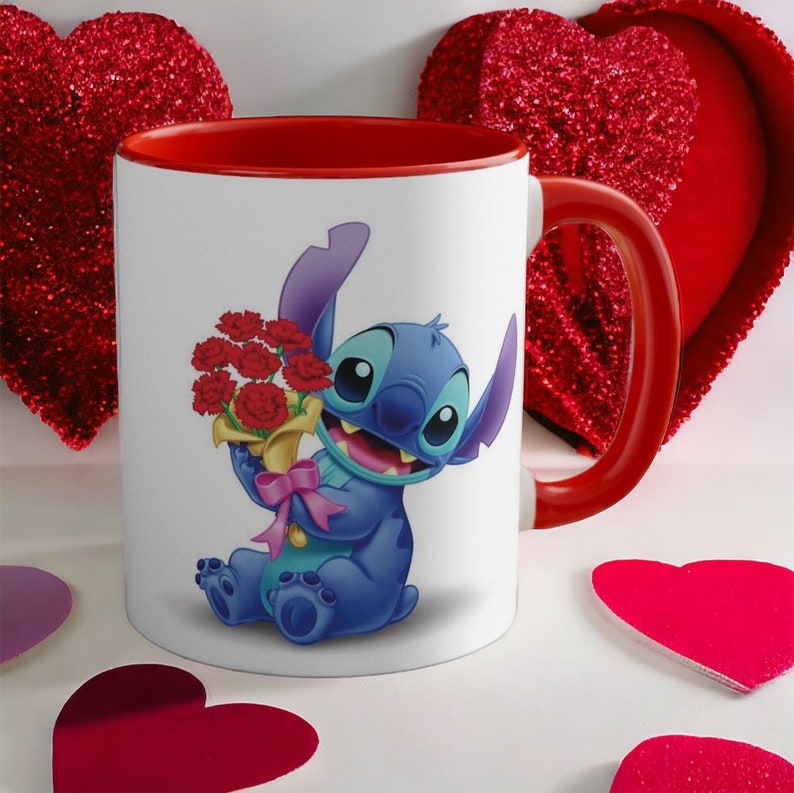 May include: A white ceramic mug with a red rim and handle. The mug features a cartoon image of Stitch from Lilo & Stitch holding a bouquet of red carnations. The mug is surrounded by red heart-shaped decorations.