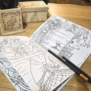May include: A set of three coloring books with black and white illustrations. The books are open to pages depicting a carousel, a group of people, and a forest scene. The books are on a wooden table with two pencils.