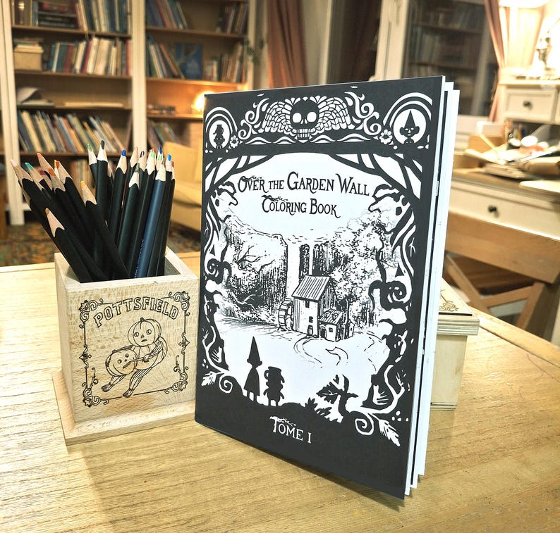 May include: A black and white coloring book titled "Over the Garden Wall Coloring Book, Tome I". The cover features a black and white illustration of a house in a forest with a character in a hooded cloak.