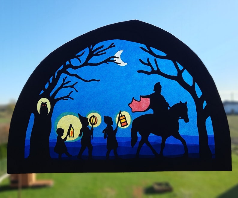 May include: A black silhouette of a figure on horseback leading a group of children carrying lanterns. The scene is set against a blue night sky with a crescent moon and stars. The children are walking through a forest with trees on either side of the path.