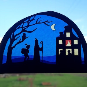 May include: A blue and black paper craft depicting a night scene with a house, a tree, an owl, a crescent moon, and two figures walking. The house has a red window and yellow windows. The figures are silhouetted.