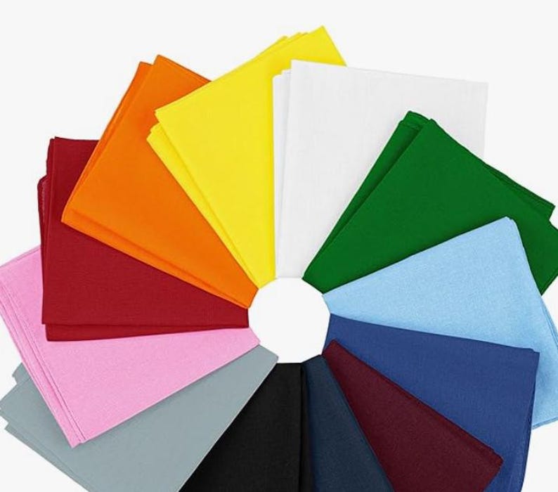 Puede incluir: Una colecci&oacute;n de servilletas de tela cuadradas y coloridas dispuestas en un patr&oacute;n circular. Las servilletas son de varios colores, incluyendo rojo, naranja, amarillo, verde, azul y negro. Las servilletas est&aacute;n cuidadosamente apiladas.